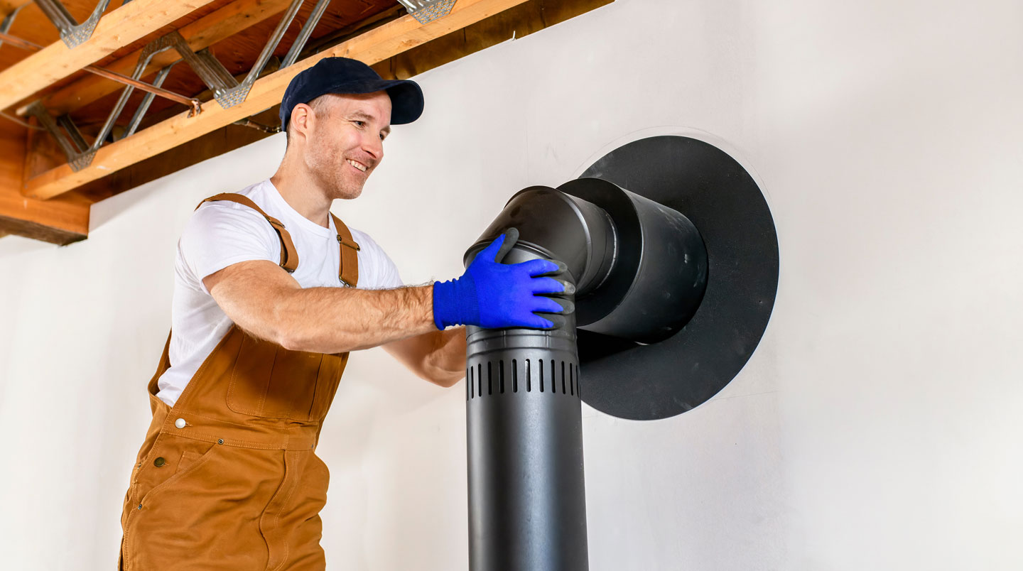 Technicien certifié RGE en train de raccorder un conduit de fumée lors de l'installation d'un poêle à bois dans une maison